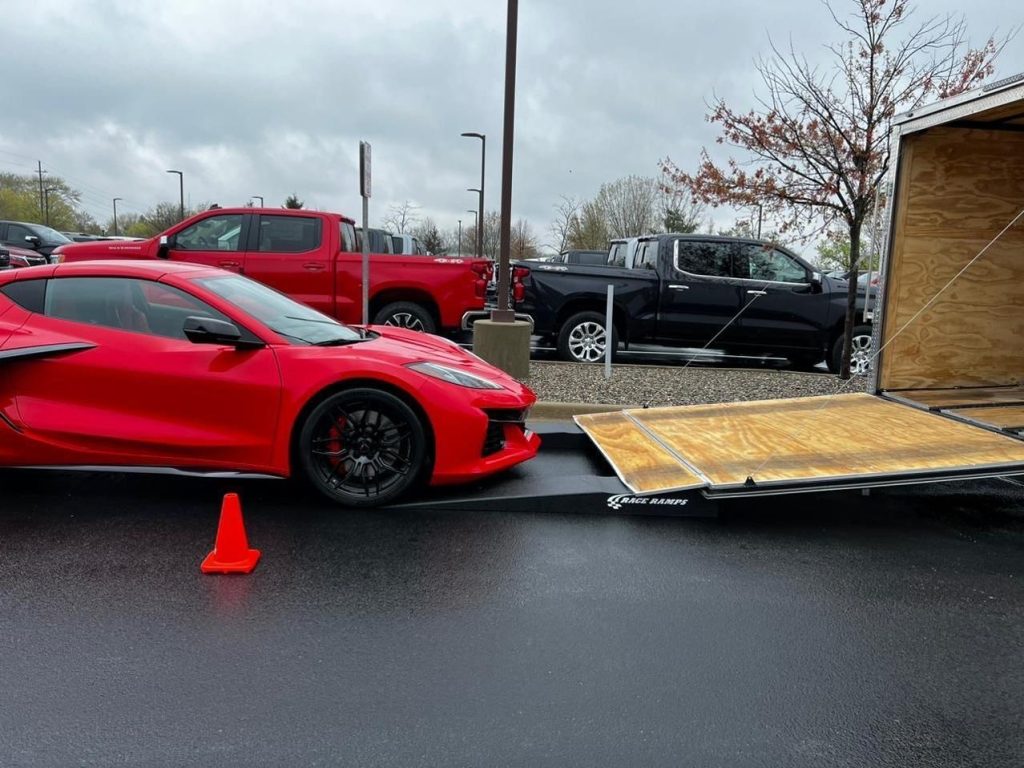 Red Chevrolet Corvette being loaded onto an enclosed trailer using low-angle race ramps for delivery to the National Corvette Museum in Bowling Green, Kentucky.