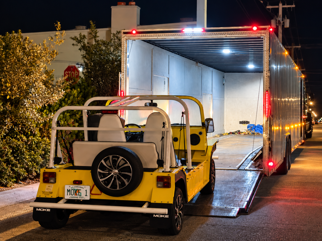 Yellow Moke loading into an enclosed auto transport trailer at night